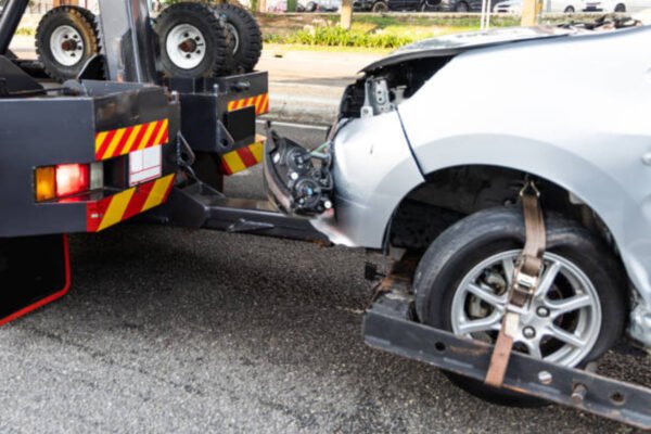 Car breakdown: Tow truck lifts damaged car, illustrating what to do if your car breaks down.