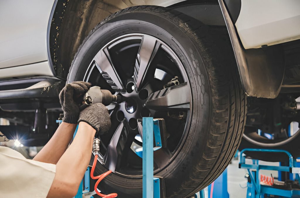 Mechanic performing tire repairs with an impact wrench on a car wheel.