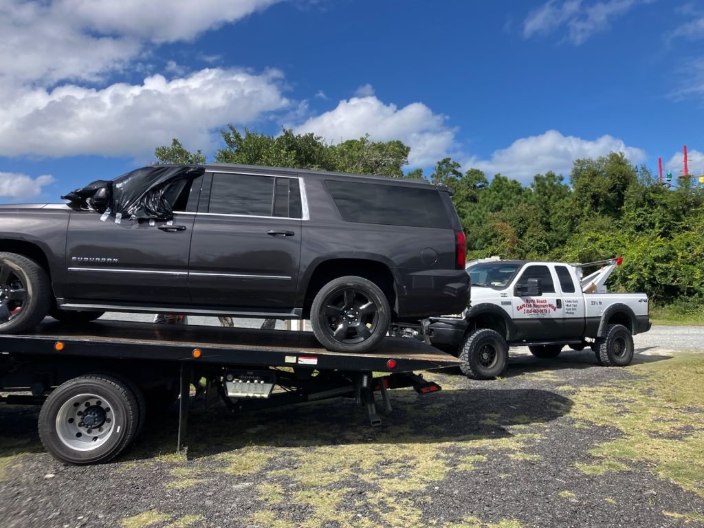 About us: Tow truck company loading a dark gray SUV onto a flatbed tow truck.